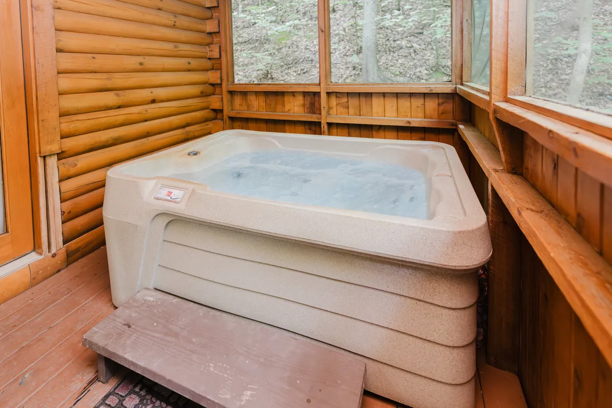 An inviting indoor hot tub with wooden walls and large windows that open up to beautiful nature views. The space is designed for relaxing, socializing, and enjoying sunsets or stargazing while immersed in soothing warmth.