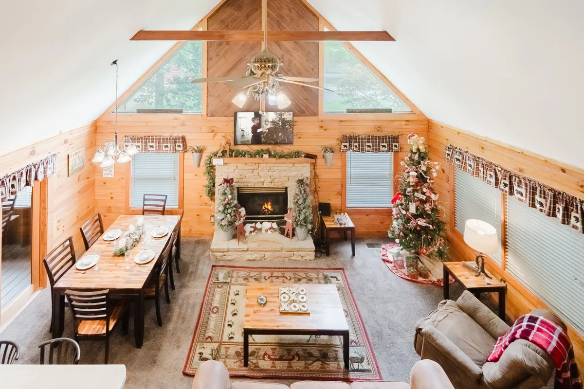 This image features a living room with a fireplace, a dining table, a plush sofa, and a beautifully decorated Christmas tree. The space is festively adorned, radiating warmth and cheer. The open-plan design seamlessly connects the lounge area with the dining space, inviting group gatherings and celebrations.