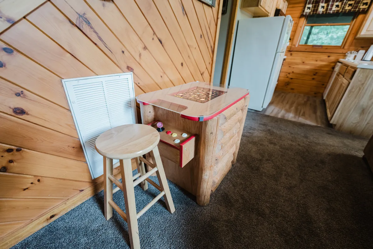 A cozy game area showcases a wooden game table and stool, set against warm wood paneling. The inviting setup hints at family game nights and fun group activities, key entertainment elements mentioned in the section.