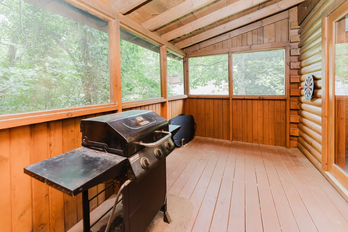 A cozy, wood-paneled interior with a grill and windows offering views of the surrounding nature. The space hints at social gatherings, family barbecues, and the transition from indoor comforts to outdoor excursions.