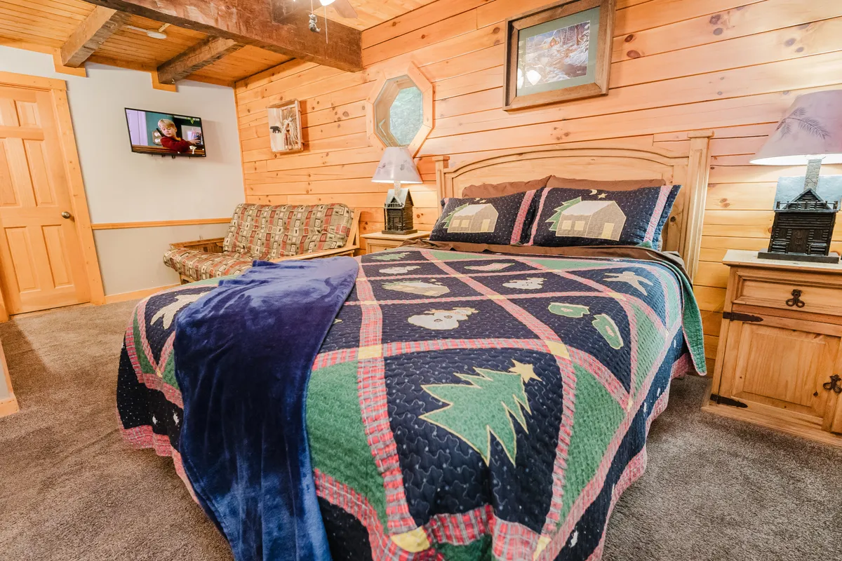 A living area with a comfortable bed and sofa, softly lit by lamps, and a television positioned for entertainment. The space is welcoming and multi-functional for relaxing or sharing stories.